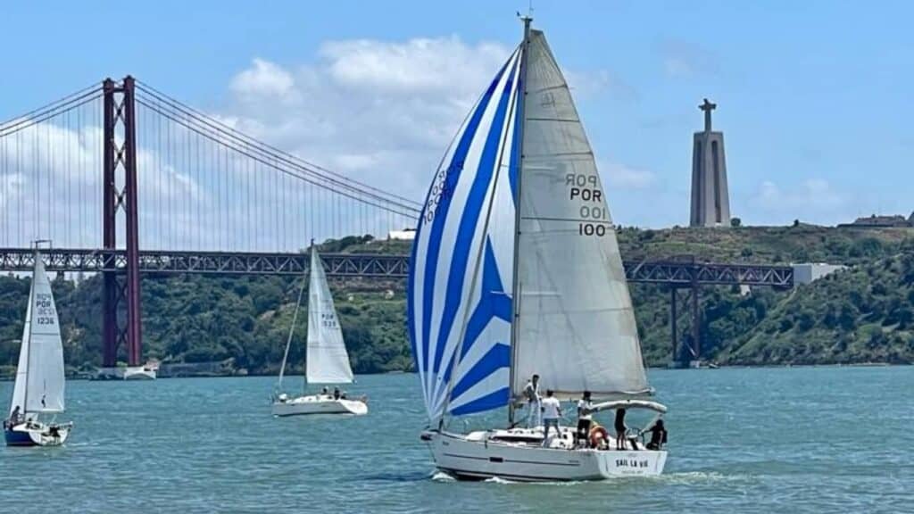 El barco "Sail la vie" surcando las aguas del río Tajo, con vistas al Puente 25 de Abril y al Cristo Rey.