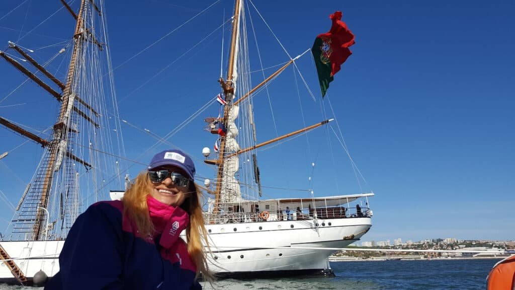 Girl on a boat, with the ship Sagres in the background, during the Volvo Ocean Race