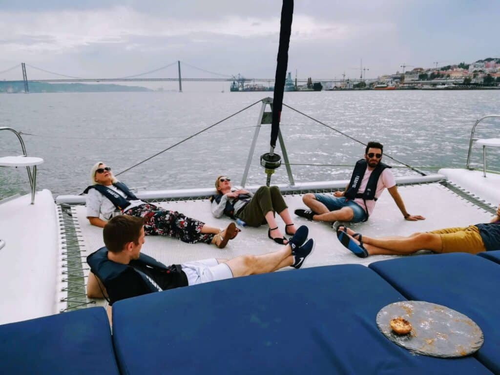 Pessoas a relaxar deitadas na rede do catamaran