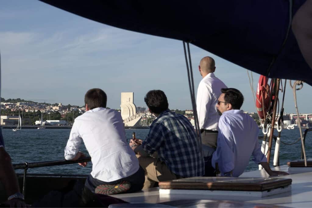 Hombres relajados en un barco mirando el Monumento a los Descubrimientos