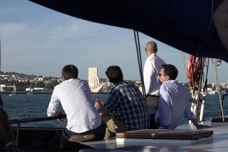Relaxed men on a boat observing the Monument to the Discoveries