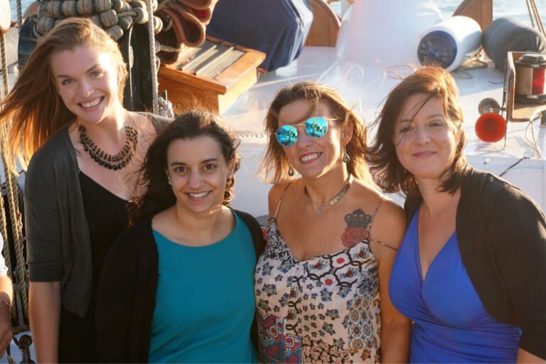 Four women aboard a classic sailboat at a Team Building event