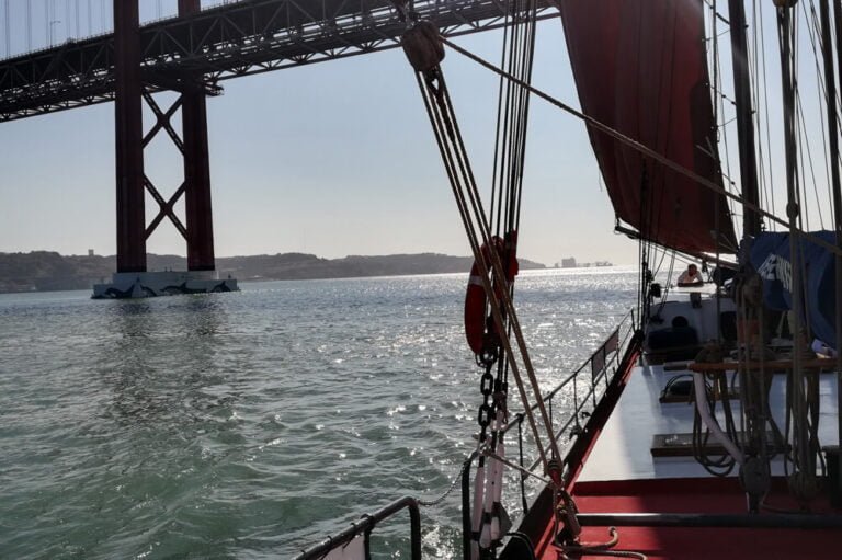 Sailboat passing under the Tagus River Bridge