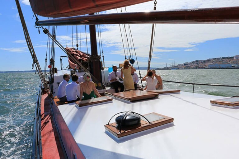 People on a sailboat viewing Lisbon in the distance during a sunny day