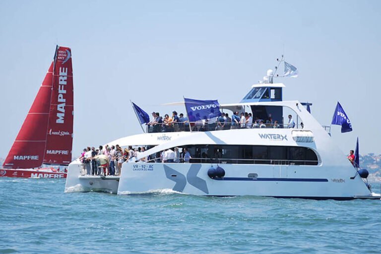 People aboard a catamaran watching the Volvo Ocean Race regatta