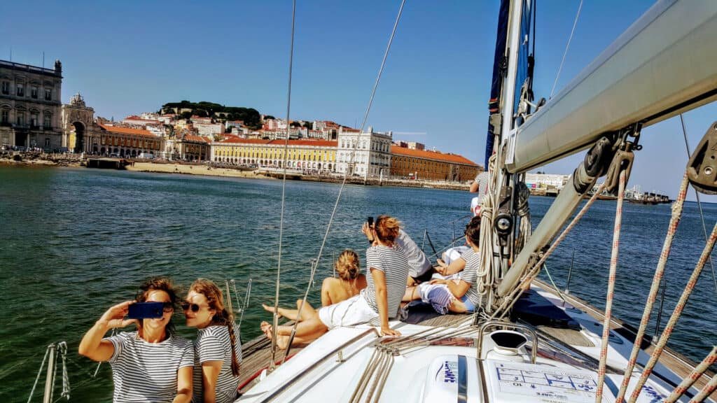 Pessoas sentadas no veleiro a contemplar Lisboa