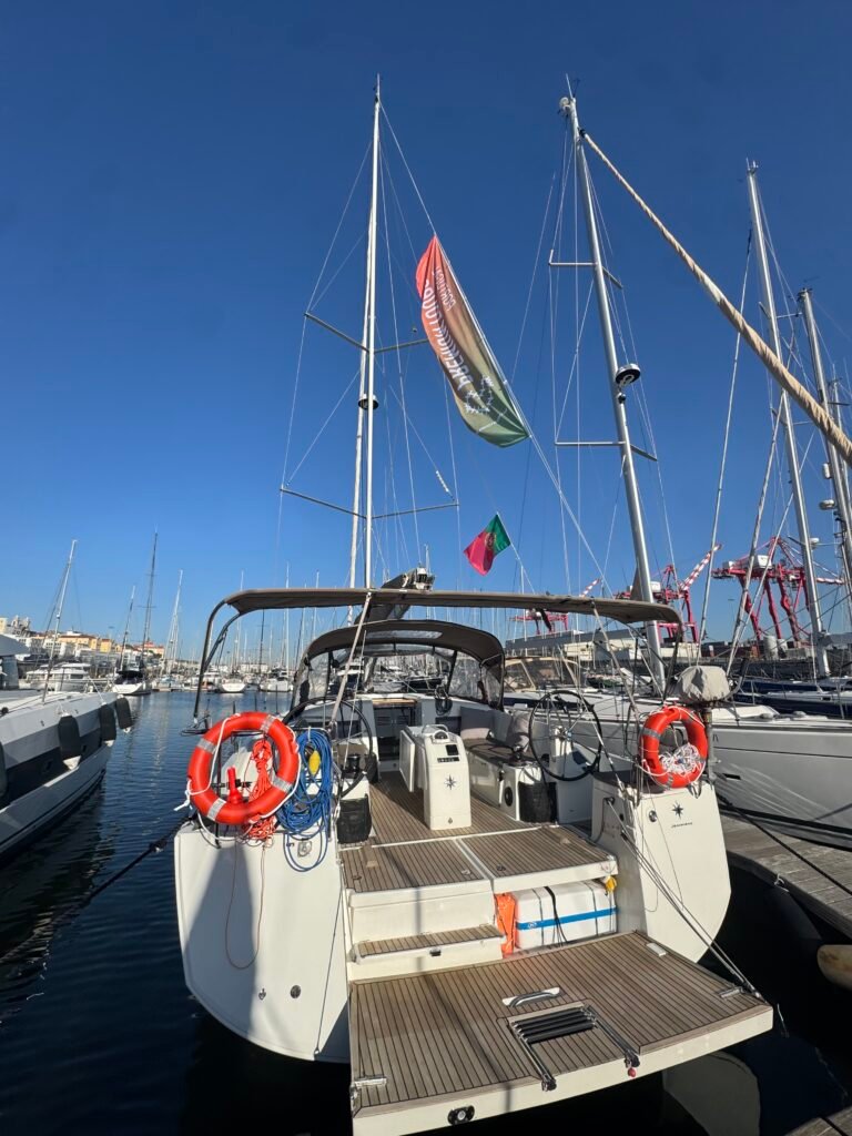 Parte traseira (popa) do veleiro Maharani ancorado, mostrando o convés em madeira e espaço de lazer.