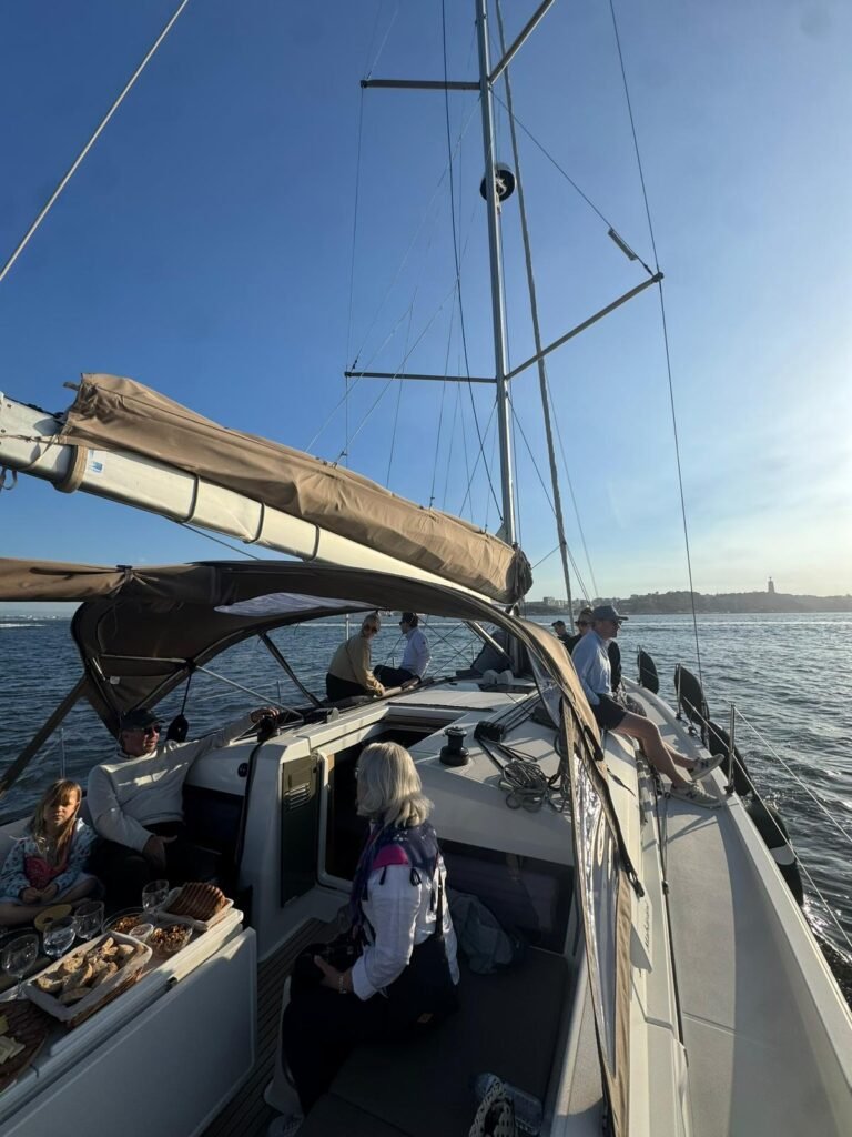 Grupo de amigos a desfrutar de um passeio de barco em Lisboa a bordo do veleiro Maharani durante o dia.