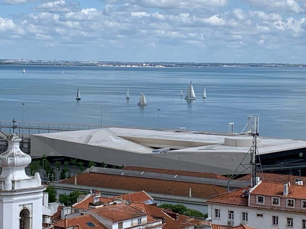 Vista de Alfama para o rio Tejo, onde navegam vários veleiros.