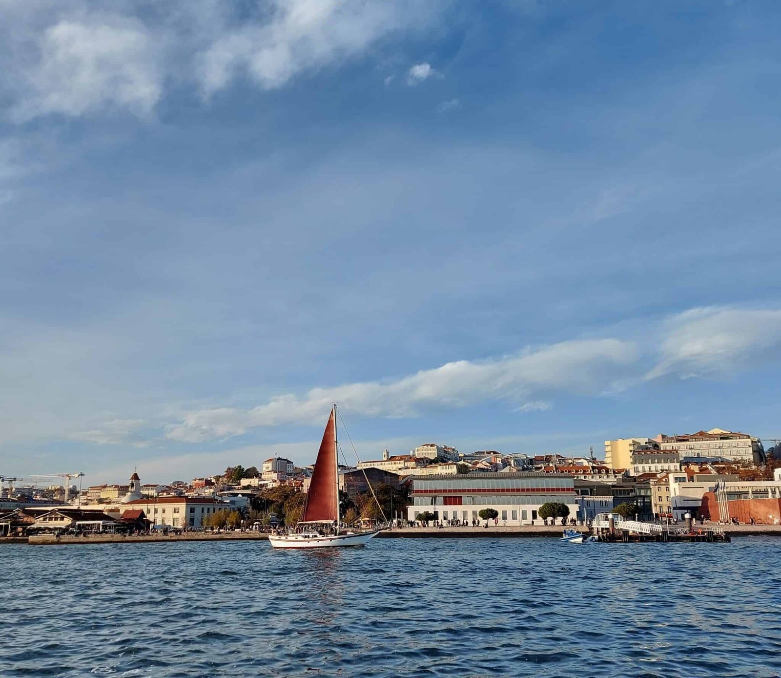 Cais do Sodré visto desde el río Tajo y un velero de velas rojas