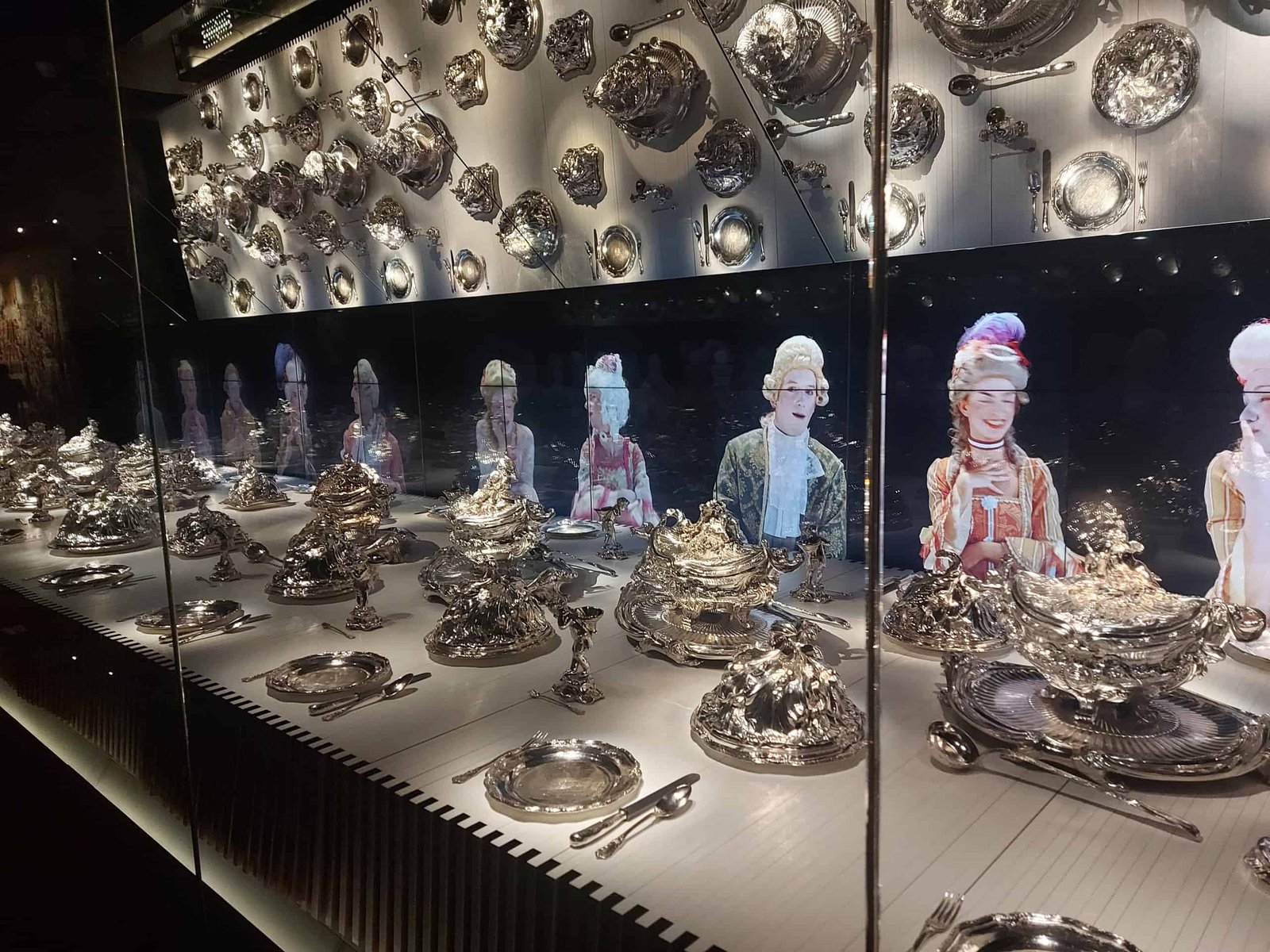 Silver meal service presented on a long table, with virtual characters, dressed in period