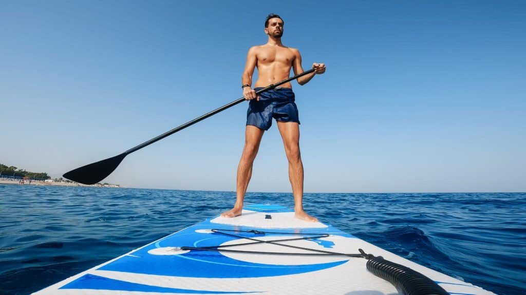Perspectiva de baixo para cima de um homem praticando stand up paddle