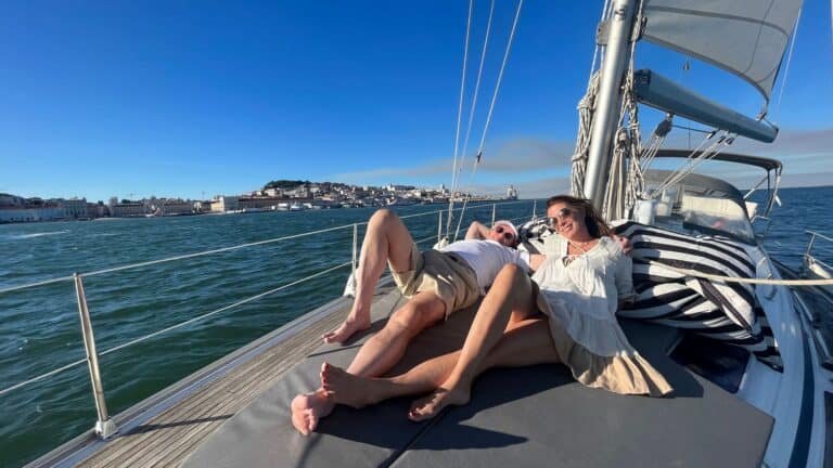 Pareja disfrutando del día soleado, acostados en la colchoneta del velero