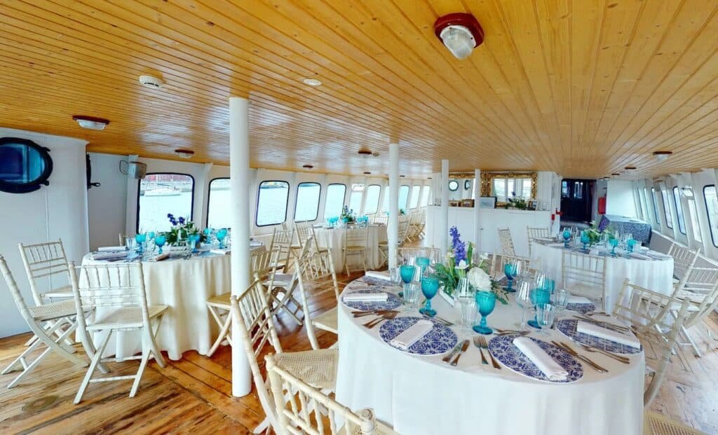 Deck interior panorâmico configurado para serviço de refeição, com mesas entoalhadas e detalhadas com loiça
