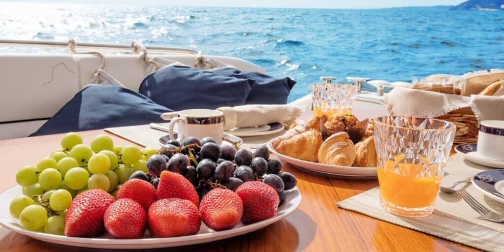 Fruta, croissant e sumo de laranja servidos à mesa do barco. Prontos para iniciar a manhã com o seu brunch no rio