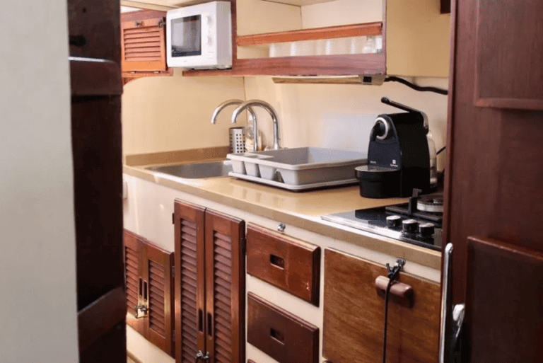 Galley equipped with a coffee machine, sink, dishes, stove, and microwave
