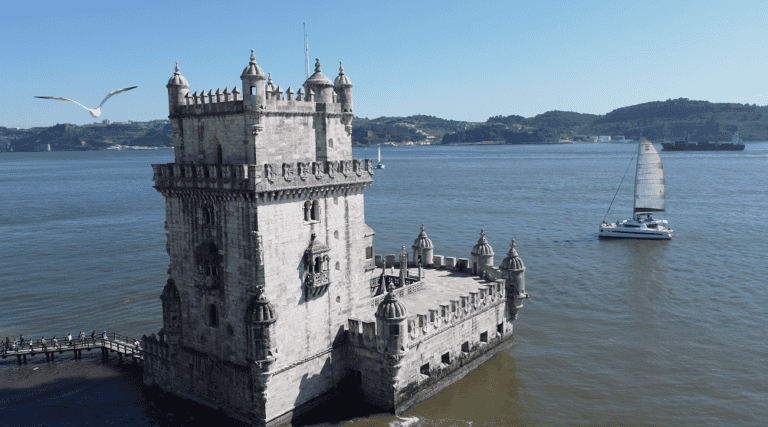 Catamaran sailboat navigating near the Belém Tower, on the Tagus River