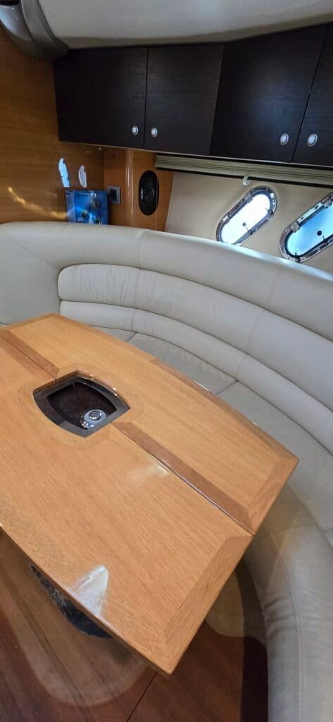 The boat's cozy interior with a U-shaped sofa and wooden table, perfect for meals or leisure time