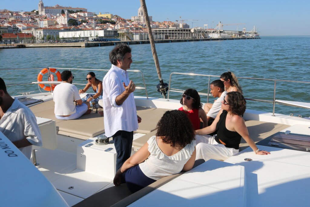 Concierges de prestigiados hotéis de Lisboa a partilhar experiências enquanto navegavam pelo Tejo, com o cenário icónico da cidade ao fundo