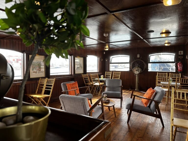 A more intimate and sophisticated lounge area, with comfortable armchairs, low tables, and decorative plants, creating a "private club" atmosphere.