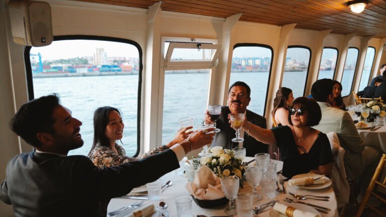 Guests toast at beautifully decorated tables, with the view of the Tagus River and Lisbon's port area visible through the windows