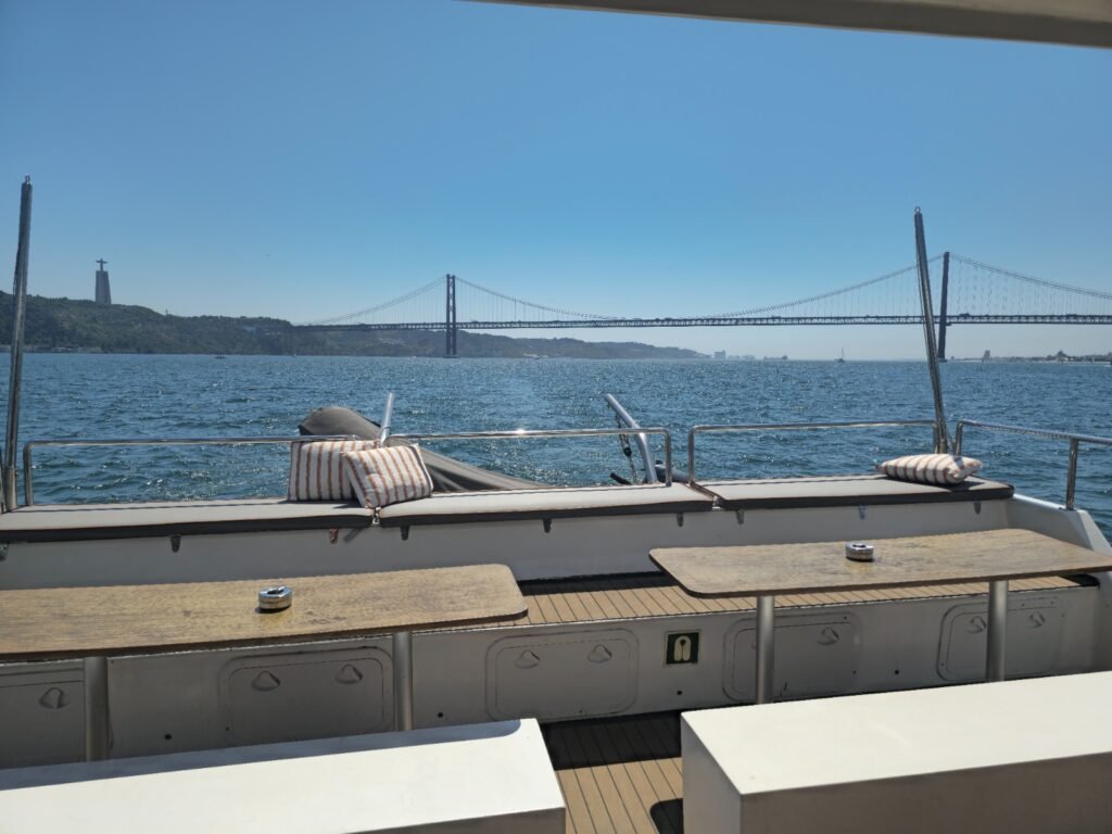 Mesas de madera y bancos blancos minimalistas en la cubierta exterior de un catamarán moderno.