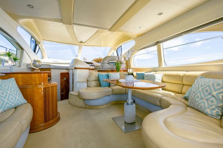 Lujoso interior del yate Azimut 46 con sofá en forma de U, mesa central y acabados de madera.
