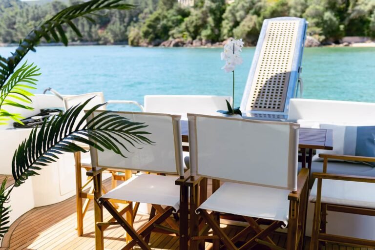 Mesa de comedor exterior en la popa de un yate de lujo Azimut 46 con sillas blancas.