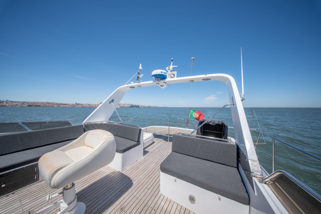 Flybridge com sofás em tom cinzento escuro, arco de radar e a bandeira de Portugal.