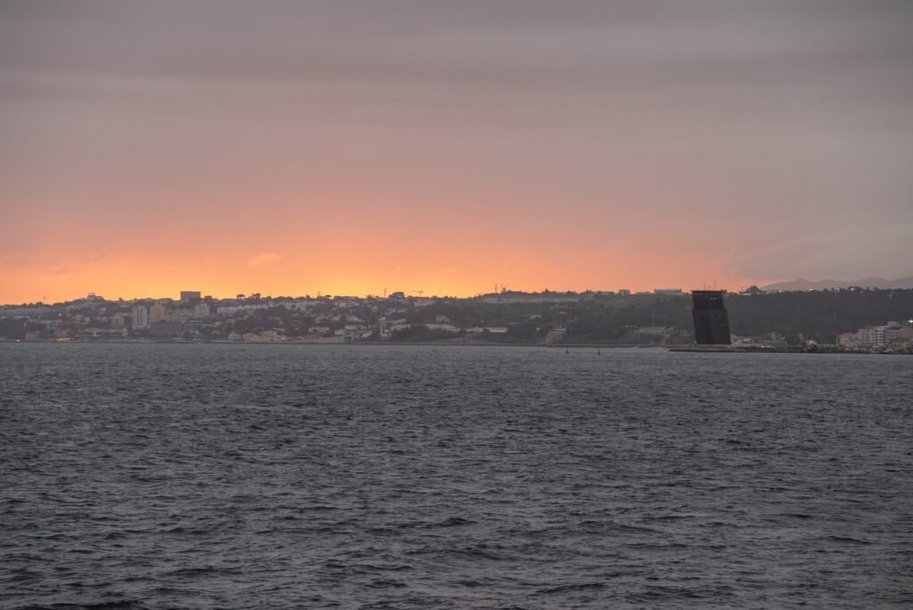 O famoso pôr do sol e a luz quente do entardecer de Lisboa refletem-se no horizonte, proporcionando o ambiente descontraído ideal para o início do evento corporativo