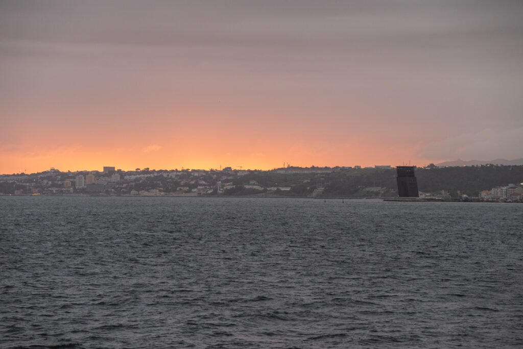 La famosa puesta de sol y la luz cálida del atardecer de Lisboa se reflejan en el horizonte, proporcionando el ambiente relajado ideal para el inicio del evento corporativo.