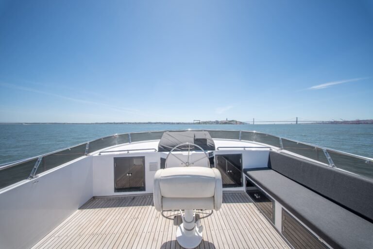 Poste de commande extérieur sur le flybridge, avec la barre, le siège du capitaine et des canapés offrant une vue panoramique sur le Tage.
