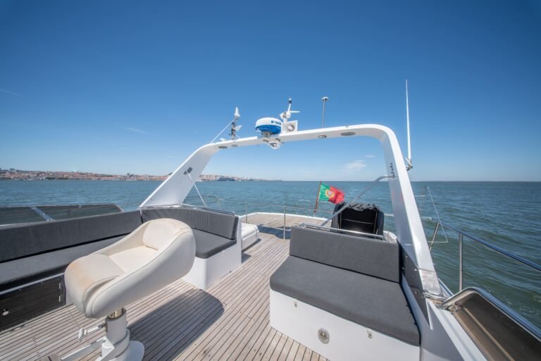 Flybridge avec des canapés gris foncé, un arceau radar et le drapeau portugais.