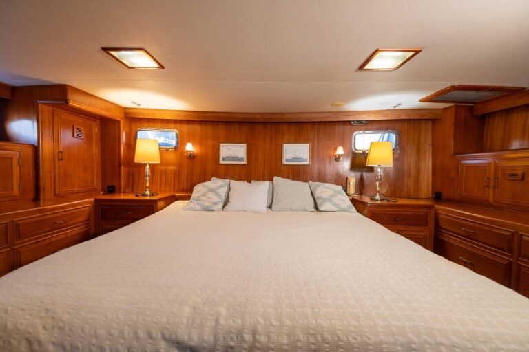 Cabine principale spacieuse et accueillante à l'intérieur du Trawler Alexander 56, mettant en valeur la décoration classique en bois précieux et un lit double confortable pour les longs voyages.