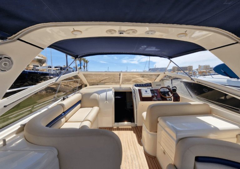 Intérieur du cockpit du Doris of Rock, avec un coin salon en cuir blanc, une table centrale et un taud Bimini qui offre de l'ombre pendant la sortie. Un espace conçu pour se détendre et passer un moment convivial à bord, lors de sorties d'une demi-journée ou d'une journée entière au départ de Vilamoura.